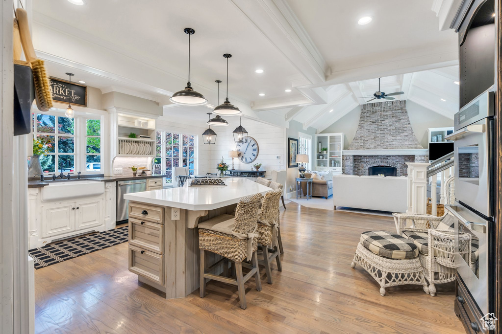 Kitchen with a ceiling fan, a sink, appliances with stainless steel finishes, light wood-type flooring, and a center island