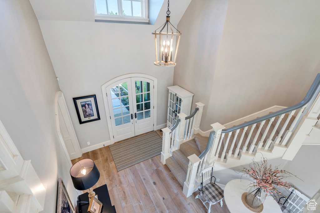 Entryway featuring a high ceiling, french doors, stairs, a chandelier, and wood finished floors