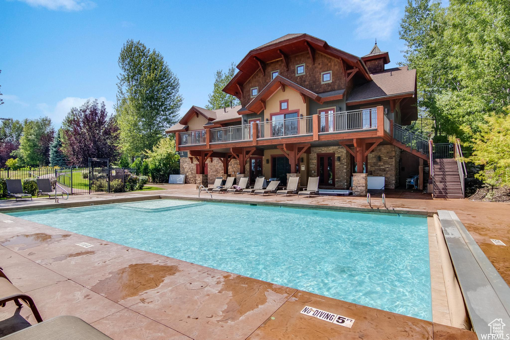 Community pool with a patio area, stairs, and fence