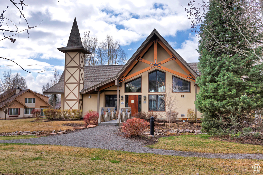 View of front of property with stucco siding, a front lawn, and a shingled roof