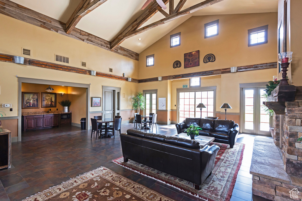 Living area with high vaulted ceiling, beam ceiling, plenty of natural light, and dark stone finish floors