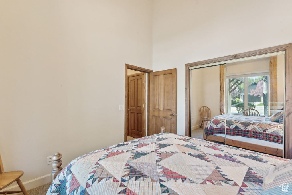 Bedroom with carpet, baseboards, a towering ceiling, and a closet