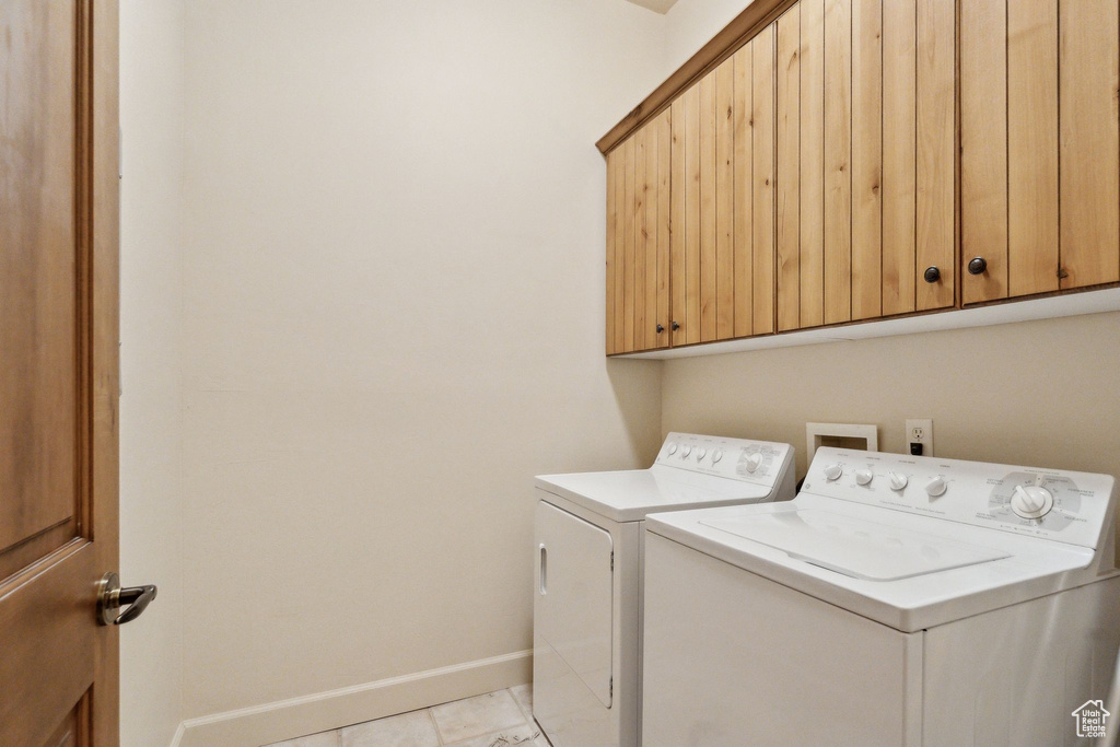 Laundry room featuring separate washer and dryer, baseboards, cabinet space, and light marble finish flooring
