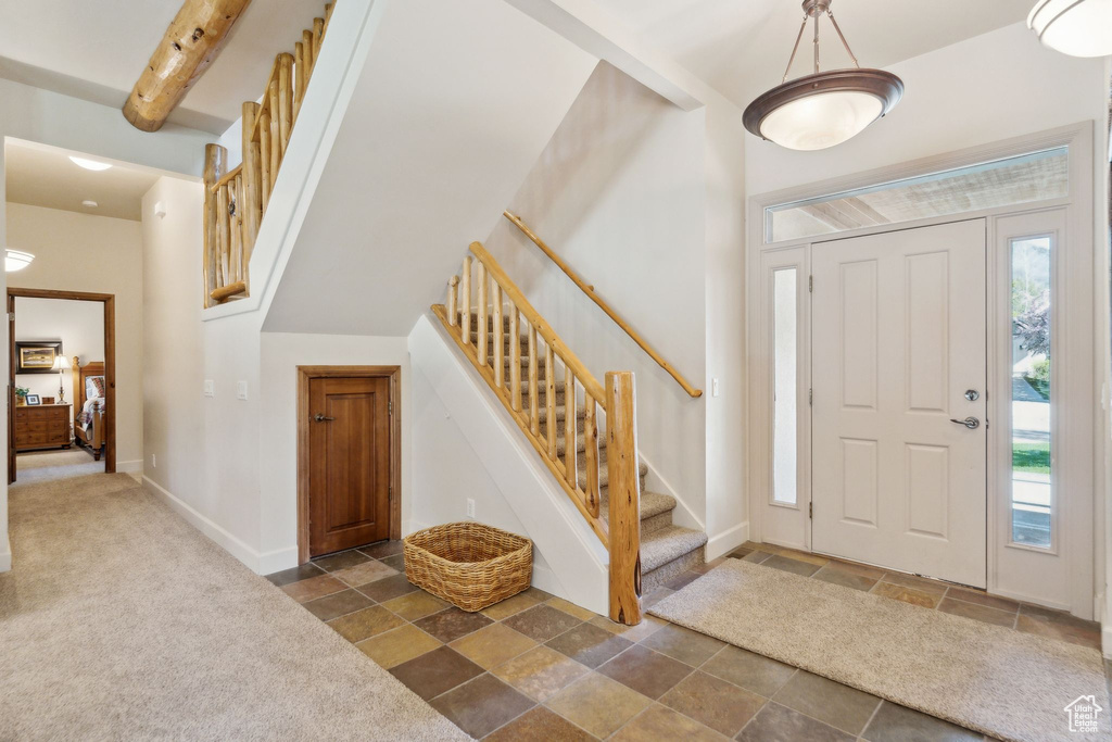 Entrance foyer featuring stone tile flooring, stairway, and baseboards