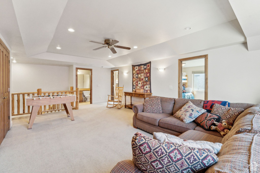 Living area featuring light colored carpet, recessed lighting, ceiling fan, a raised ceiling, and baseboards