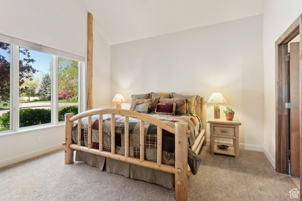 Carpeted bedroom featuring baseboards and high vaulted ceiling