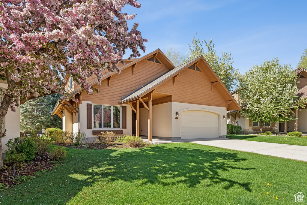 View of front of home featuring an attached garage, stucco siding, concrete driveway, and a front lawn