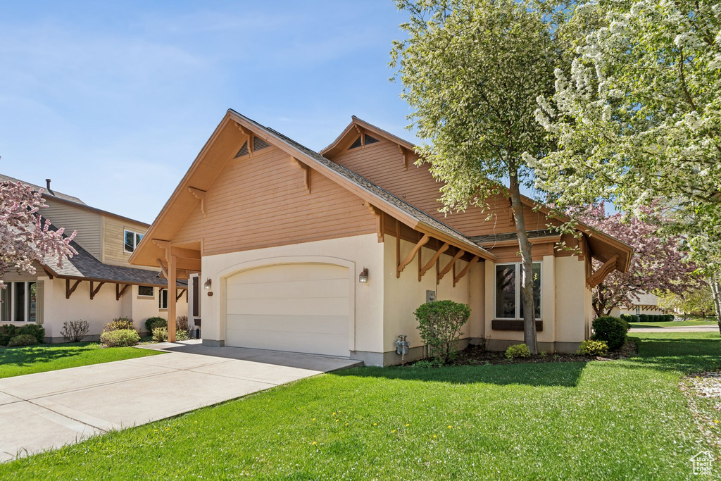 View of front of house featuring an attached garage, driveway, a front lawn, and stucco siding