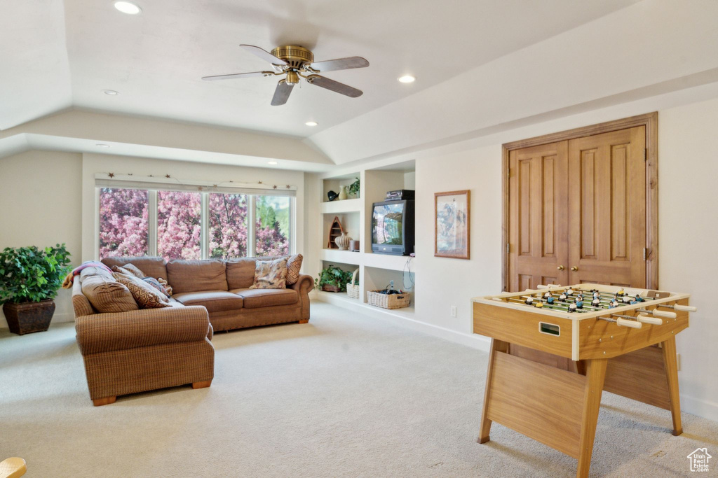 Carpeted living room featuring vaulted ceiling, recessed lighting, built in shelves, ceiling fan, and baseboards