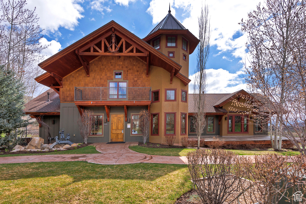 View of front of home with a balcony and a front yard
