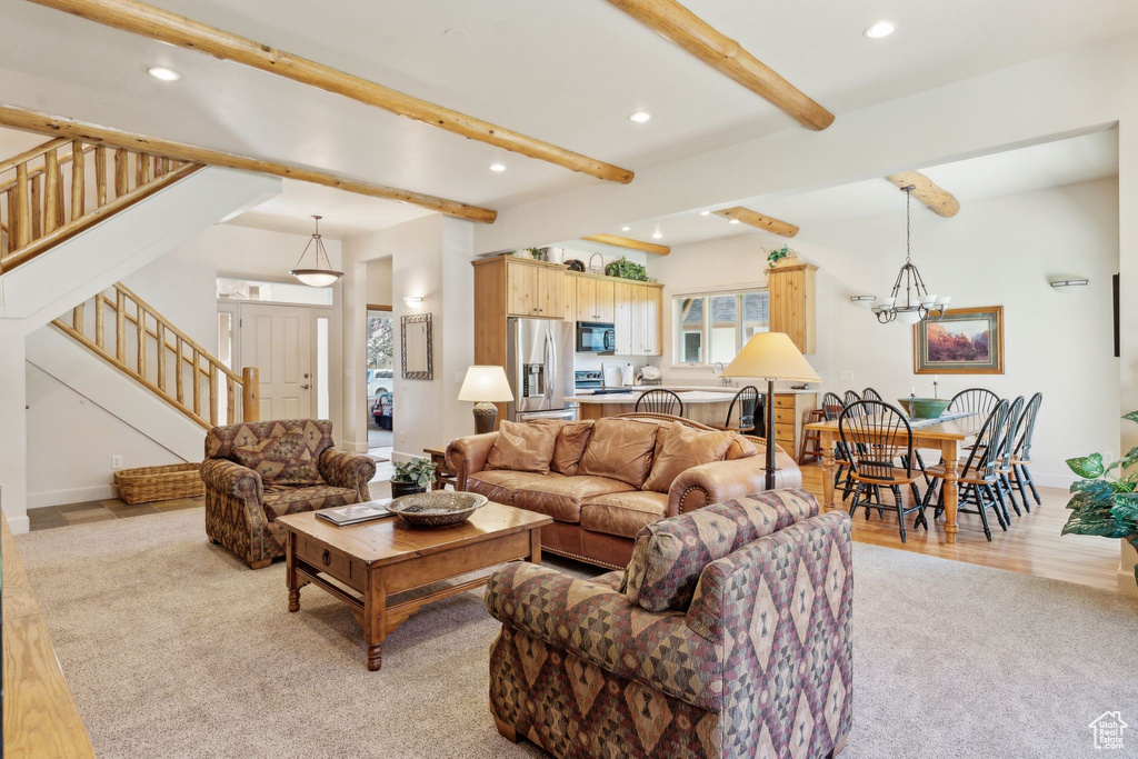 Living room with beamed ceiling, stairs, recessed lighting, a chandelier, and light colored carpet