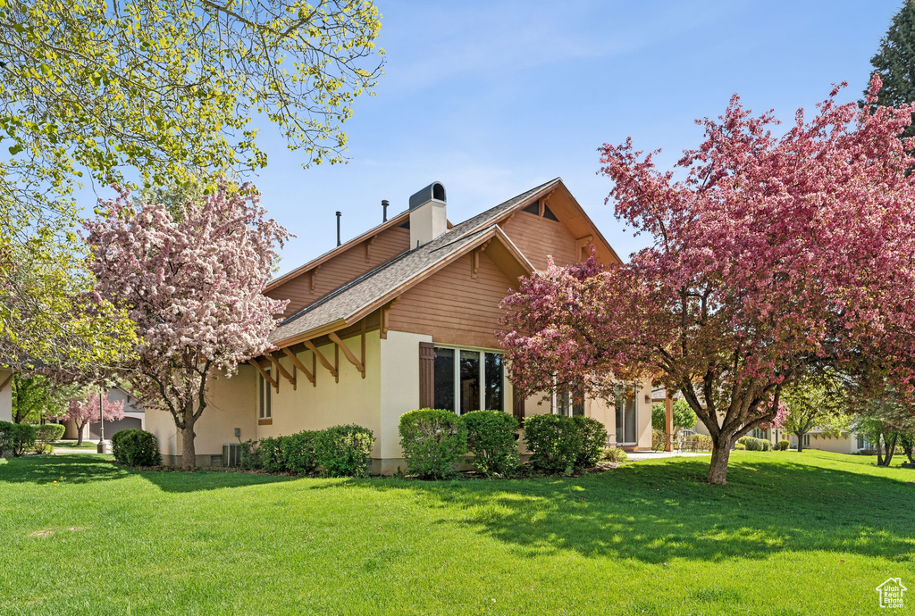 View of home's exterior with a yard, a chimney, stucco siding, and a shingled roof
