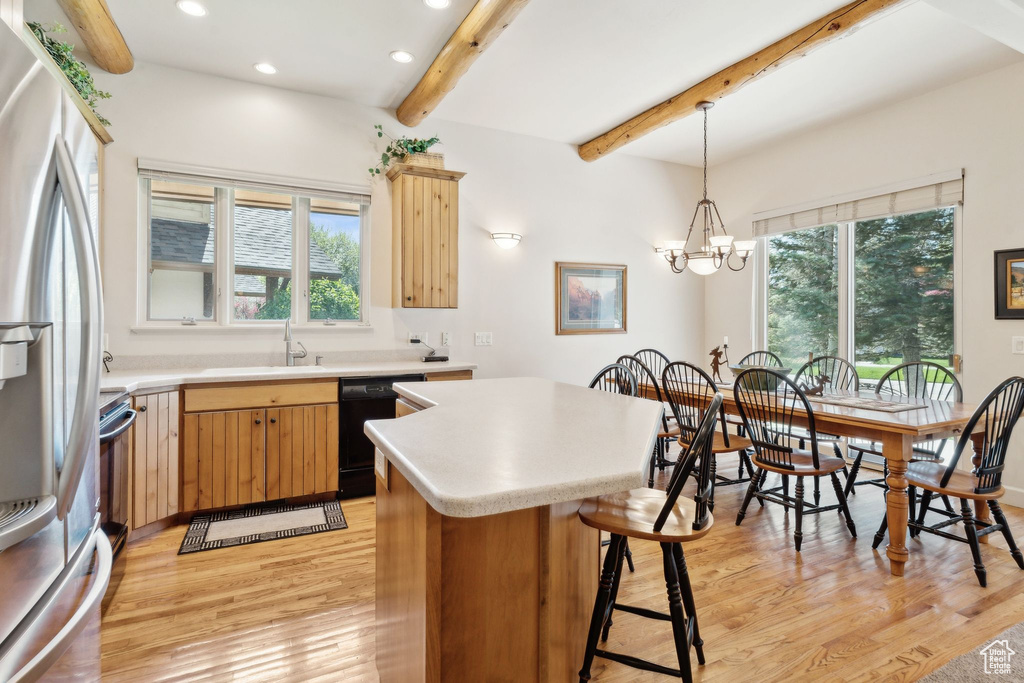 Kitchen featuring stainless steel fridge with ice dispenser, light wood-style flooring, healthy amount of natural light, beam ceiling, and light countertops