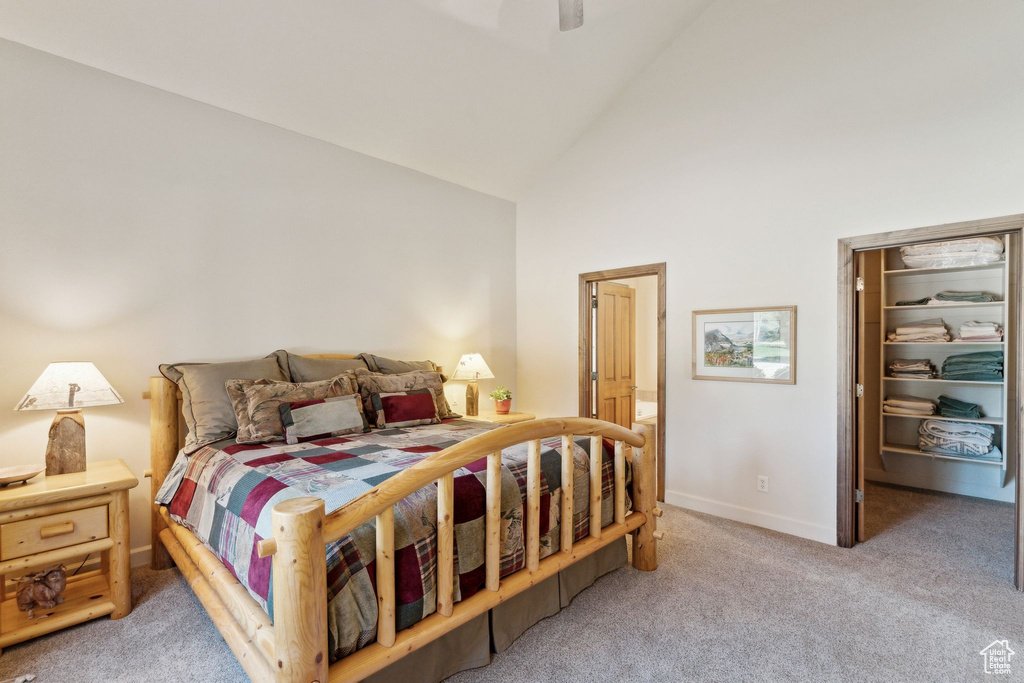 Carpeted bedroom featuring high vaulted ceiling, a walk in closet, baseboards, a ceiling fan, and a closet
