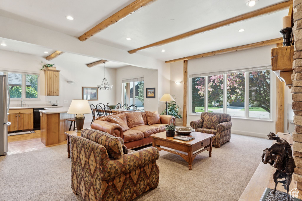 Living area with light colored carpet, recessed lighting, beamed ceiling, and a chandelier