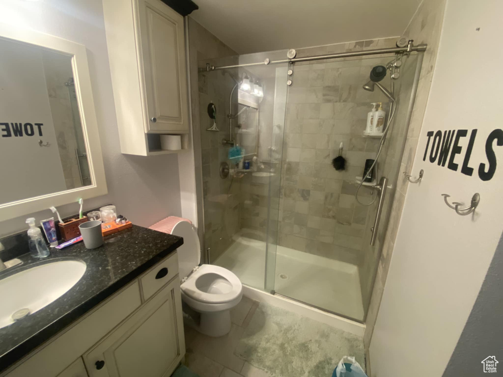 Bathroom with a shower stall, toilet, vanity, and tile patterned flooring