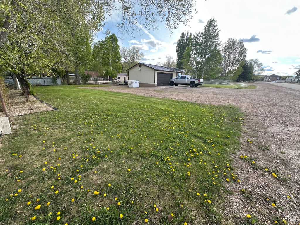 View of yard featuring dirt driveway and a garage