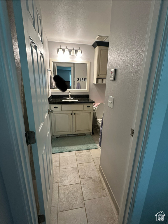 Bathroom with vanity, toilet, and a textured ceiling