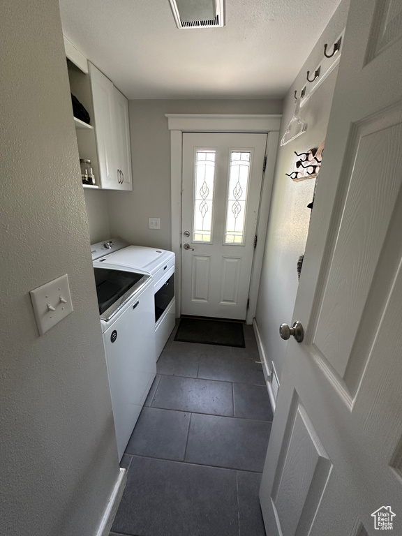 Laundry room with cabinet space, washer and clothes dryer, dark tile patterned floors, and baseboards