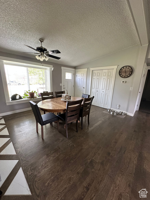 Dining space featuring dark wood-type flooring, baseboards, a textured ceiling, a ceiling fan, and vaulted ceiling