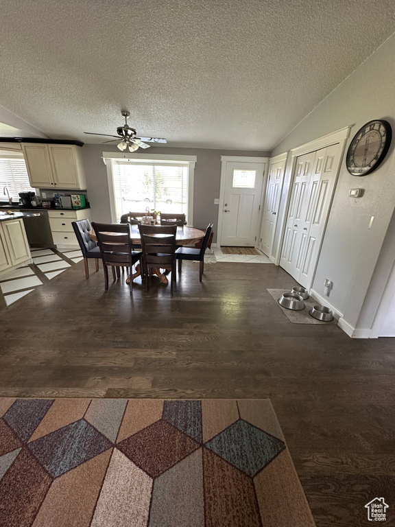 Dining room featuring a ceiling fan, dark wood-style flooring, a textured ceiling, vaulted ceiling, and baseboards