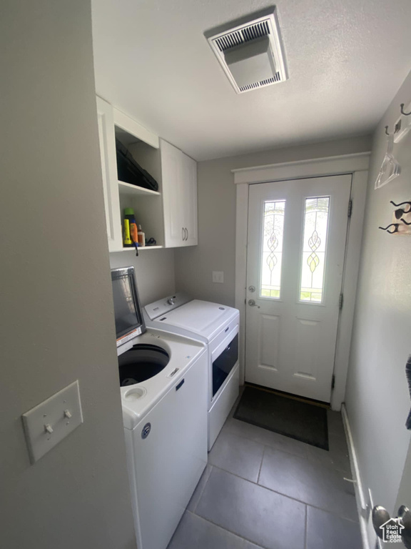 Laundry area featuring washer and dryer, cabinet space, tile patterned flooring, and baseboards