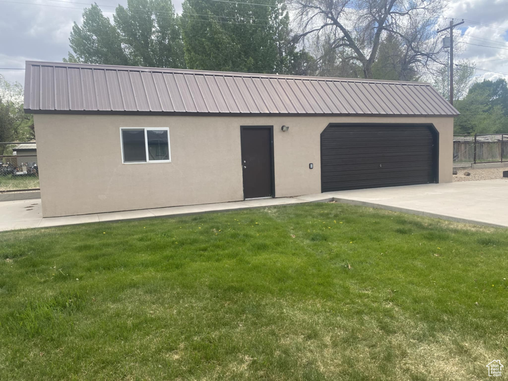 View of front facade featuring stucco siding, metal roof, driveway, and a garage