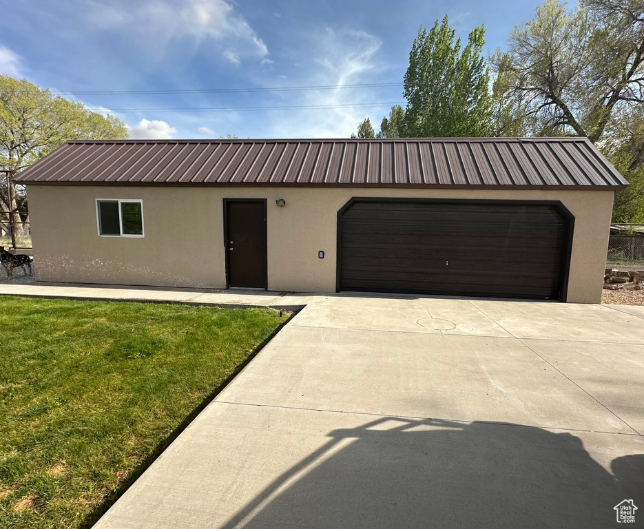 View of front of property with stucco siding, metal roof, and a front yard