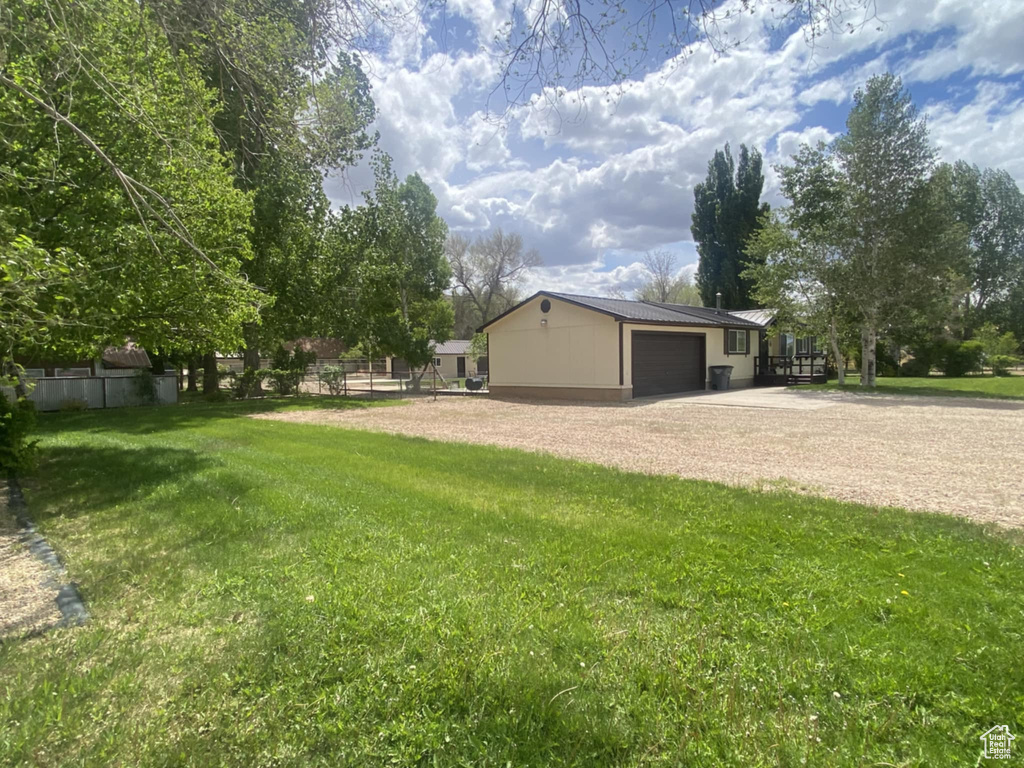 View of grassy yard with driveway and an attached garage