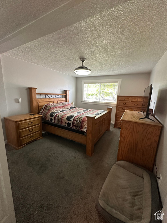 Bedroom featuring dark carpet and a textured ceiling