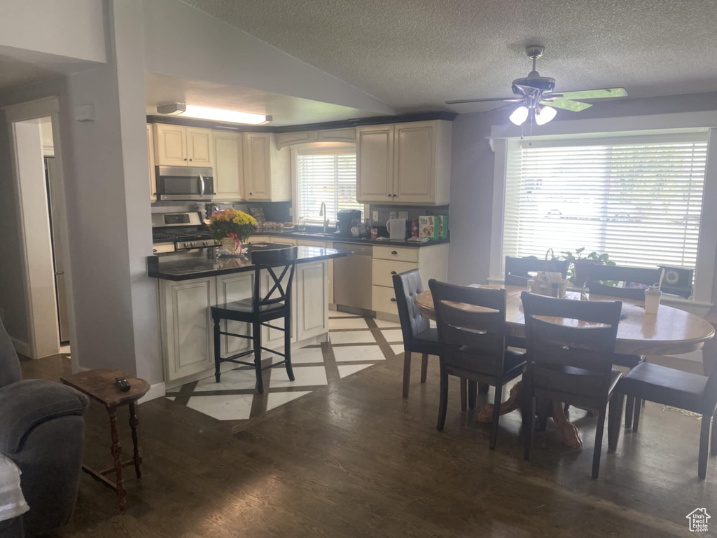 Dining area with light wood-style floors, ceiling fan, and a textured ceiling