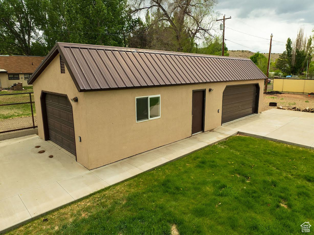 View of front of house featuring stucco siding, a garage, and an outdoor structure