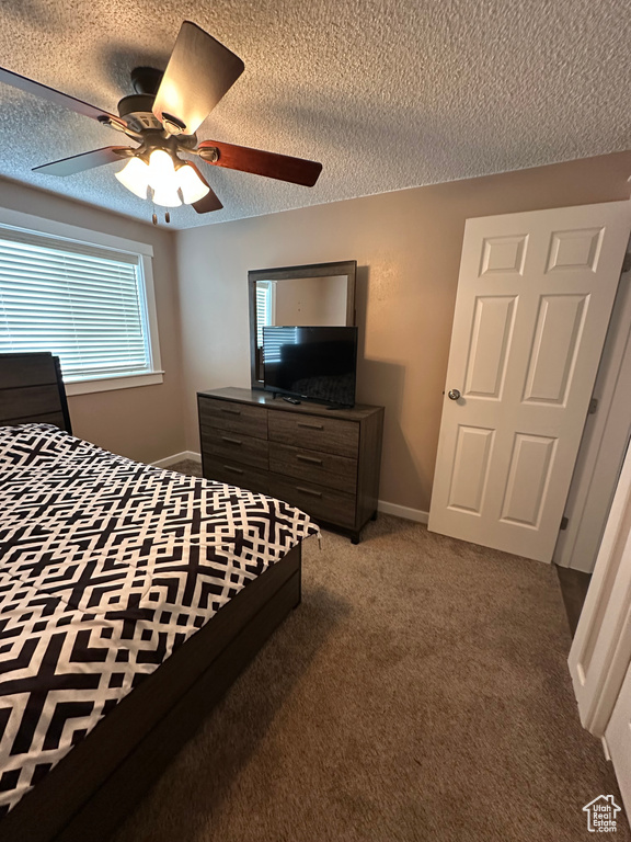 Carpeted bedroom with a textured ceiling and a ceiling fan