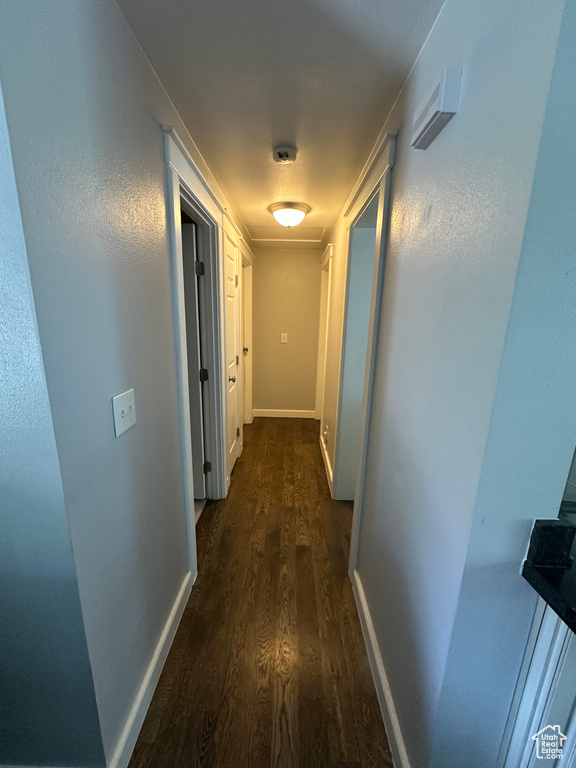 Hallway featuring dark wood-type flooring and baseboards