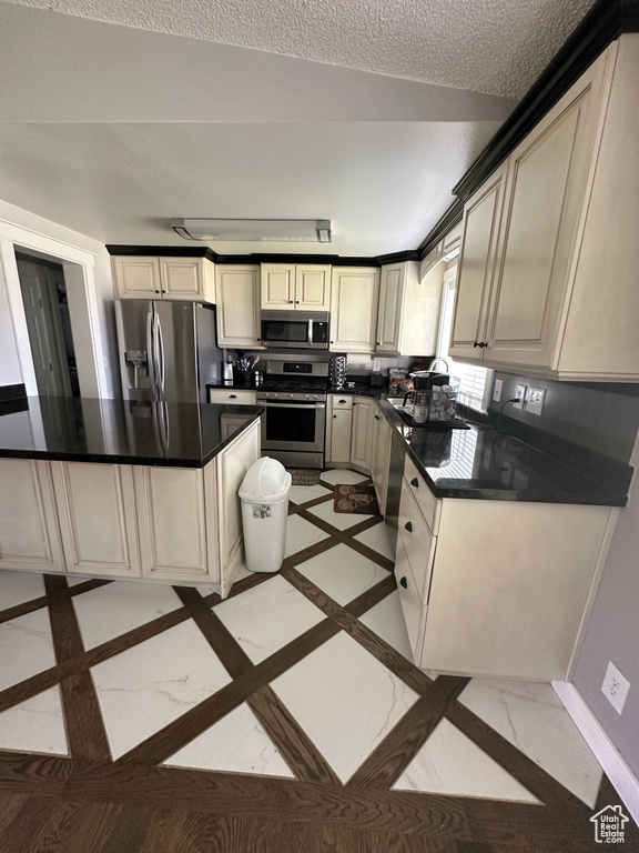 Kitchen with stainless steel appliances, dark countertops, and inlaid floor details