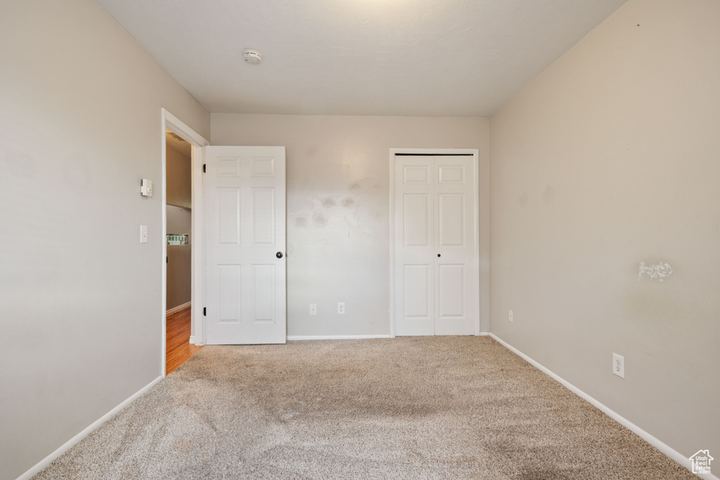 Unfurnished bedroom featuring carpet floors, baseboards, and a closet