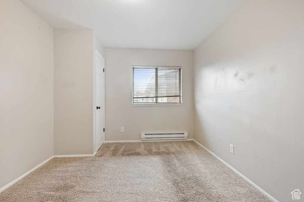 Unfurnished room with baseboard heating, carpet, and baseboards