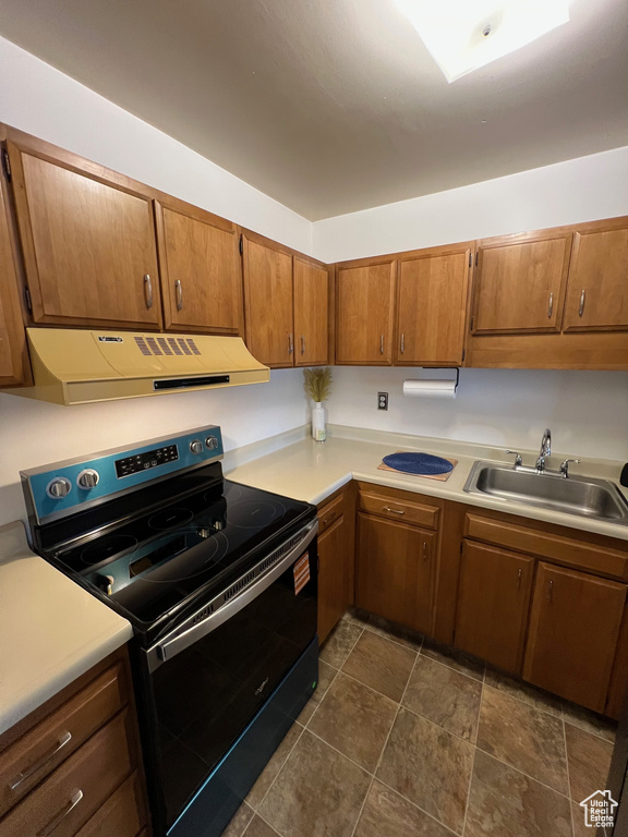 Kitchen featuring electric range, ventilation hood, a sink, and light countertops