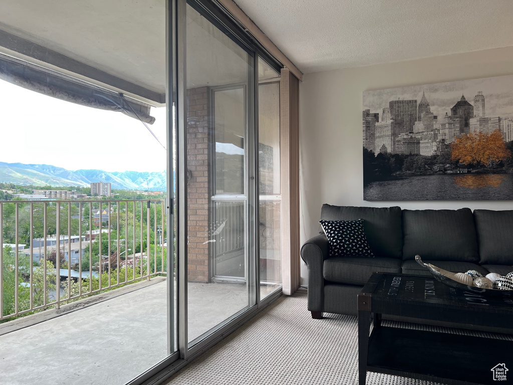 Living area with carpet floors, a wall of windows, and a mountain view