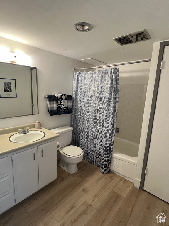 Bathroom featuring wood finished floors, toilet, vanity, and shower / bath combo
