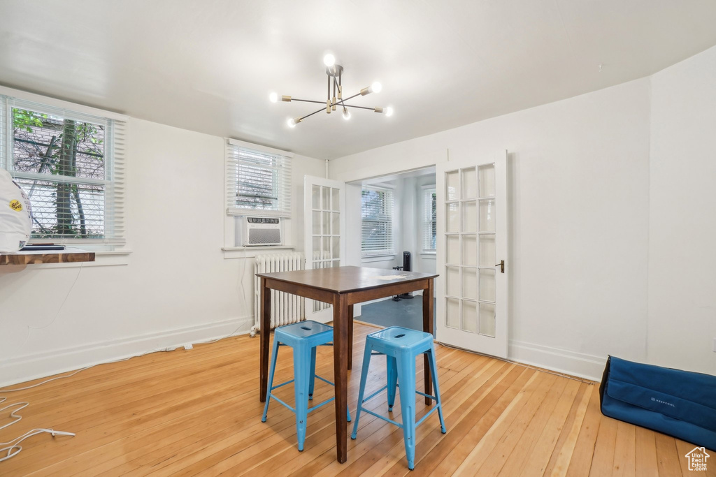 Dining area with radiator, a chandelier, light wood-style floors, and baseboards