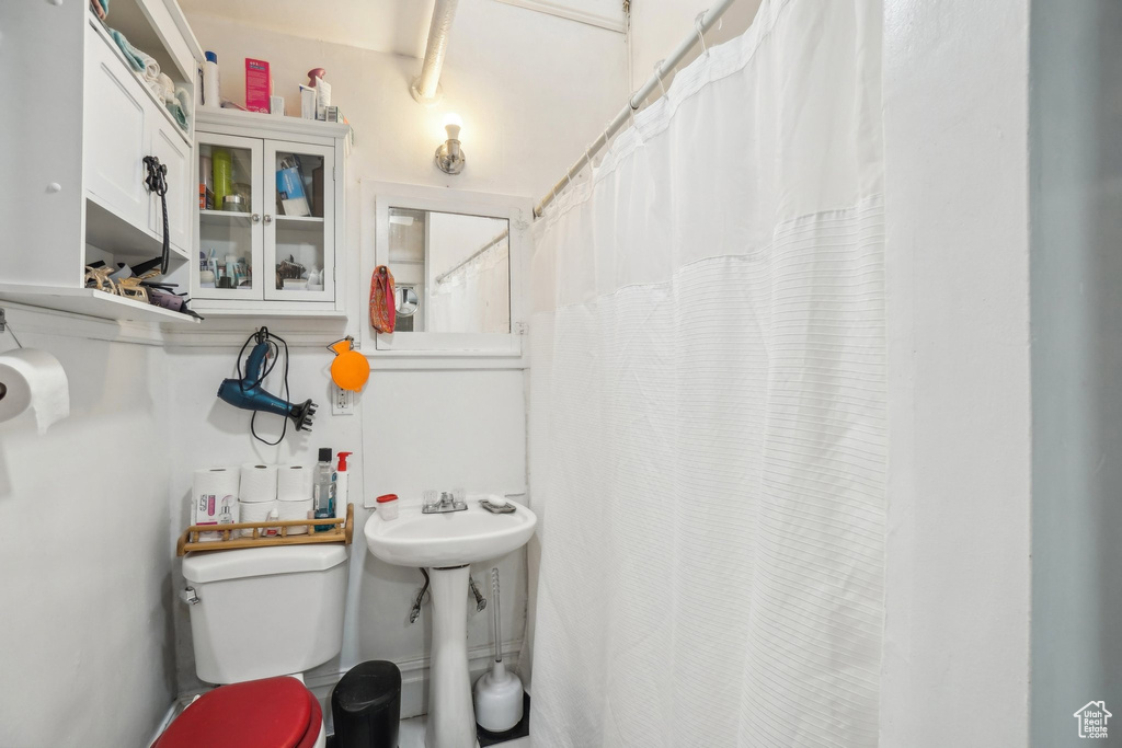 Full bath with toilet, a sink, and a shower with curtain