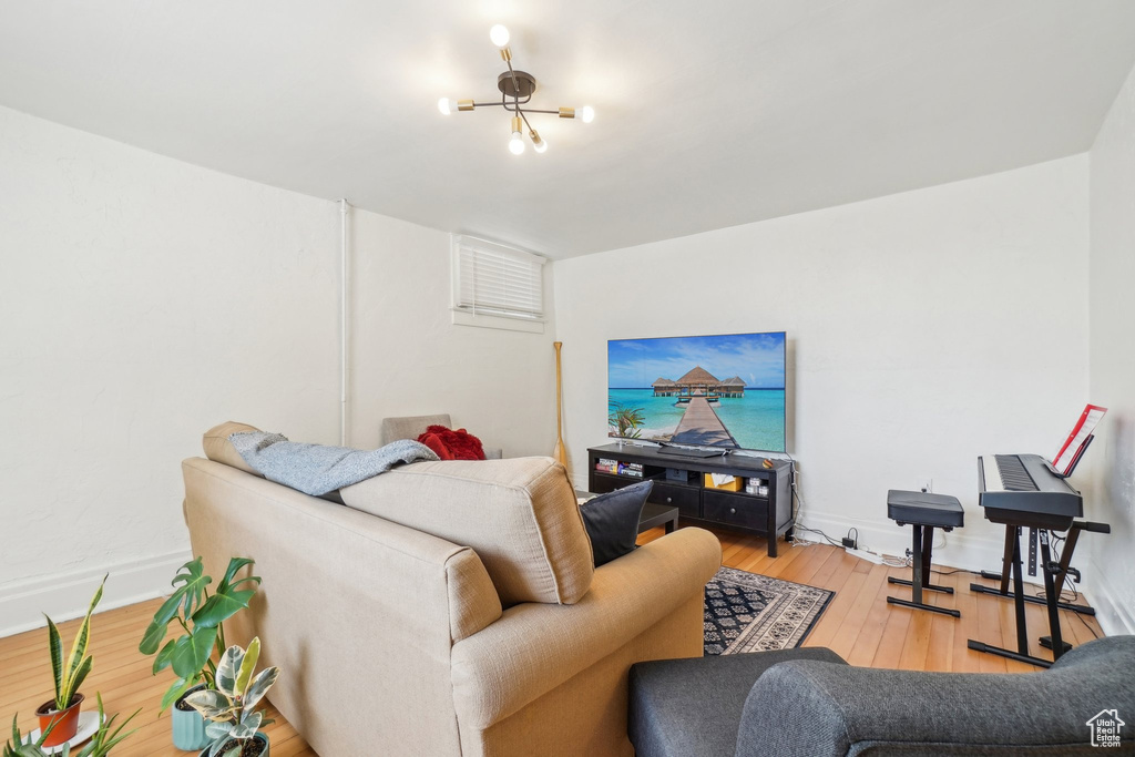 Living area featuring light wood finished floors, a chandelier, and baseboards