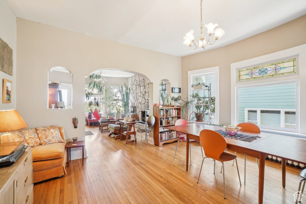 Dining space featuring a chandelier, light wood-type flooring, and arched walkways