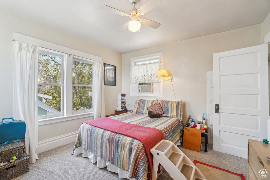 Carpeted bedroom featuring baseboards, a ceiling fan, and cooling unit
