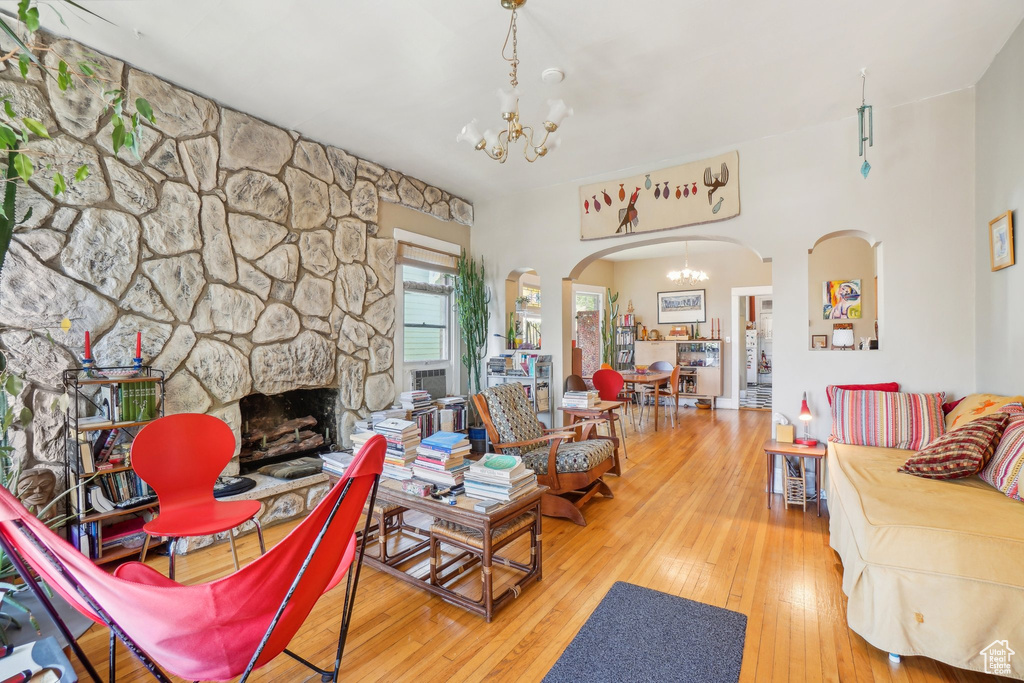 Living room featuring a chandelier, arched walkways, hardwood / wood-style flooring, and a fireplace