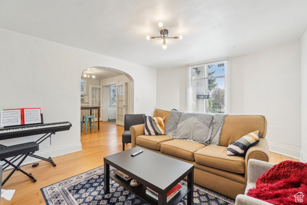 Living room with arched walkways, light wood finished floors, baseboards, and a chandelier