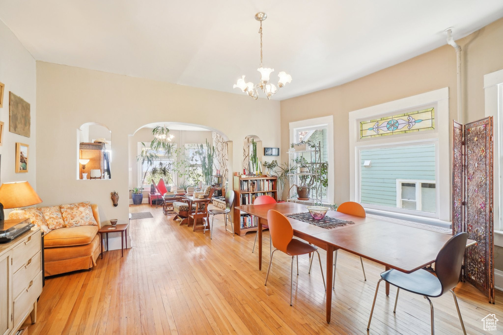Dining room with a chandelier, arched walkways, and light wood-style floors
