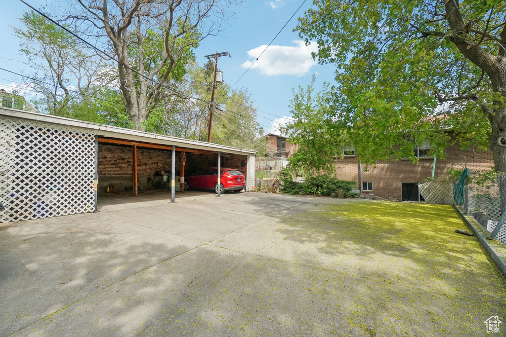 View of vehicle parking featuring fence, driveway, and a carport