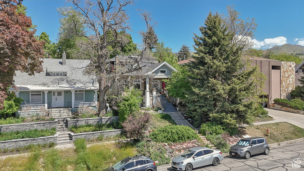 View of property hidden behind natural elements featuring stairway and a porch